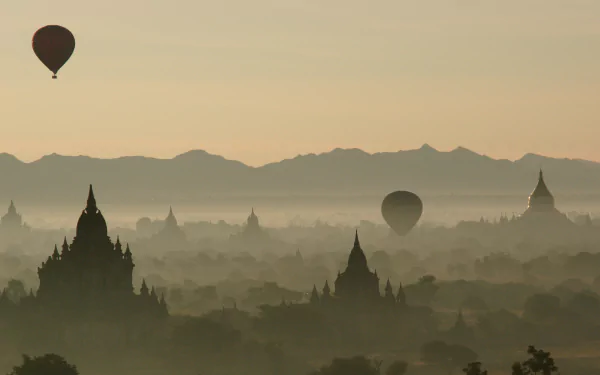 4K Ultra HD PC desktop wallpaper: hot air balloons (air vehicles) drifting over misty pagodas and temple silhouettes at sunrise with distant mountains.
