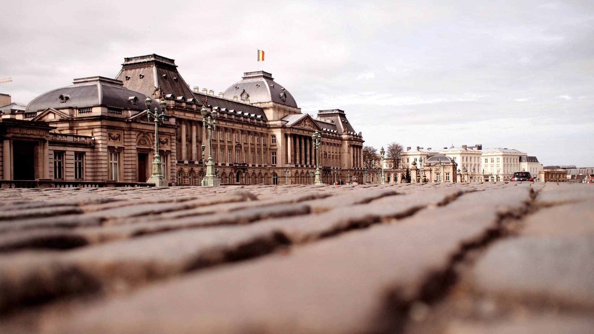 HD desktop wallpaper showcasing the Royal Palace of Brussels, a grand man-made architectural landmark under a cloudy sky.