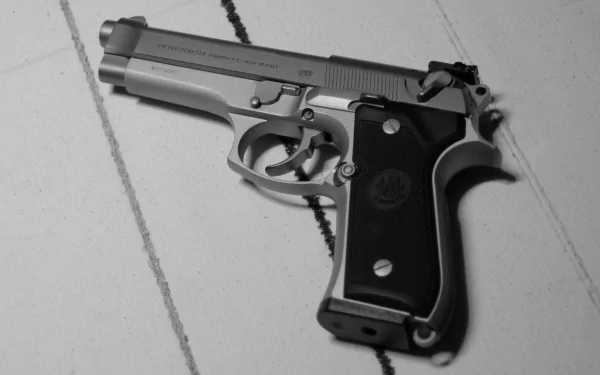 Black and white HD desktop wallpaper of a Beretta handgun resting on a tiled surface, highlighting the man-made firearm's detailed craftsmanship.