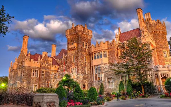 HD PC desktop wallpaper/background: Casa Loma, a man-made stone castle with turrets, towers and landscaped gardens glowing under a dramatic cloudy evening sky.