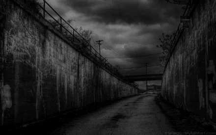 HD desktop wallpaper featuring a dark, moody road flanked by concrete walls, leading towards a bridge under a cloudy, foreboding sky. Tag: man made, road.