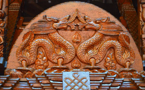 Intricate wood carving of two dragons on a Nepalese pagoda in Brisbane, showcasing traditional craftsmanship in this HD photography background.