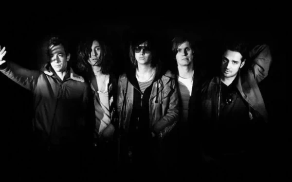 Black and white HD desktop wallpaper featuring the five members of The Strokes in a moody, shadowed group portrait.