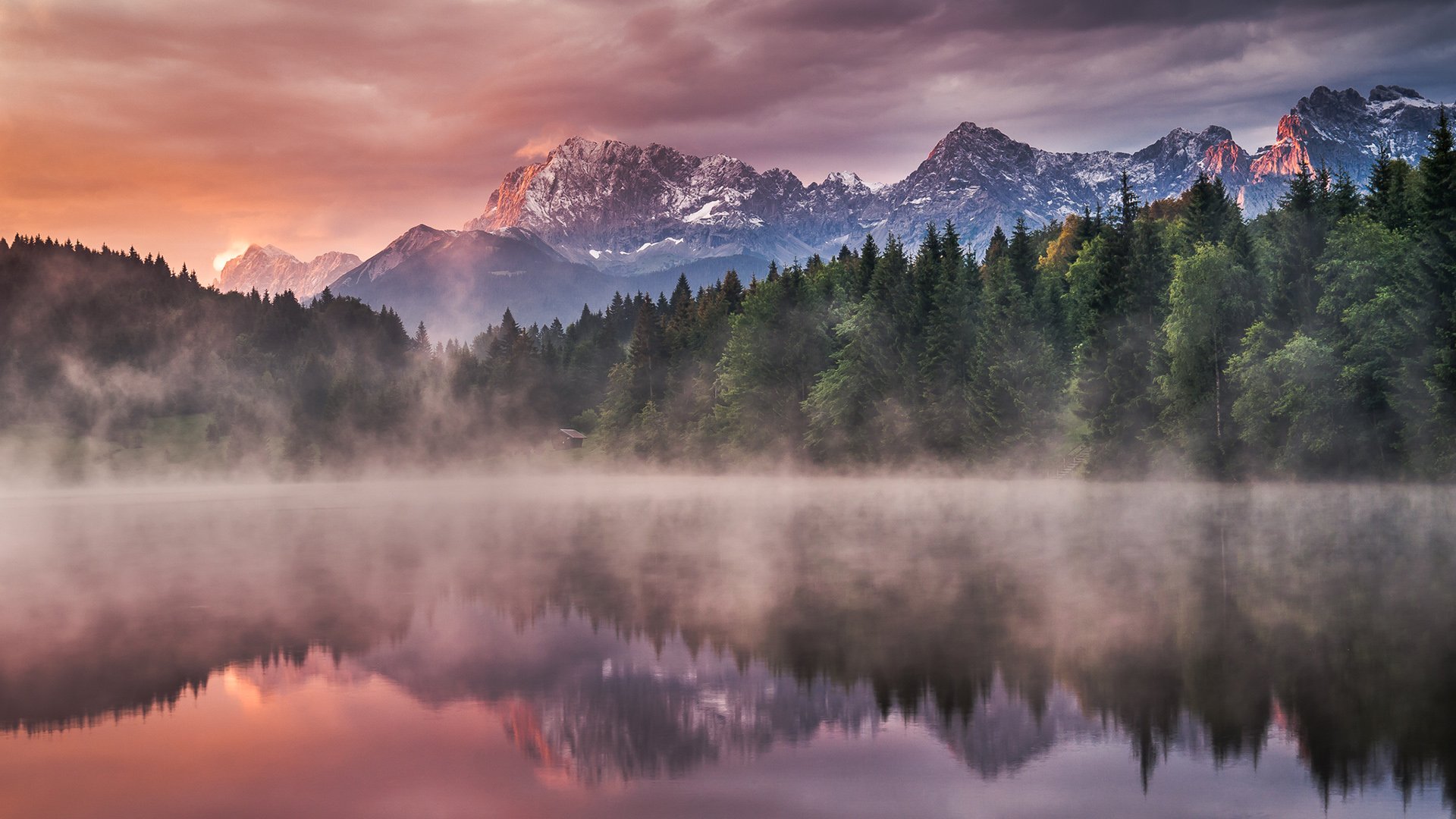 HD PC desktop wallpaper/background: misty lake reflecting pine forest and snow‑capped mountains at sunrise — serene nature landscape.
