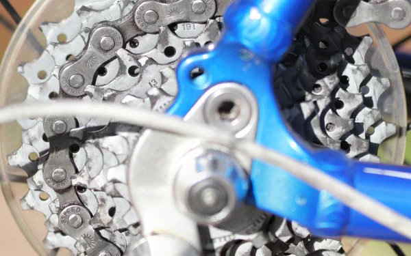 Close-up 4K Ultra HD image of a bicycle's gear cassette and blue frame, showcasing the detailed chain and mechanical components of the vehicle.