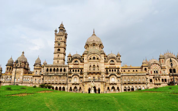 HD wallpaper showcasing the grand man-made Laxmi Vilas Palace in Vadodara against a cloudy sky and lush green lawn foreground.
