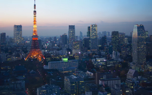 Twilight view of Tokyo Tower illuminated amid the cityscape of Tokyo, Japan. The HD image captures the iconic man-made structure and surrounding skyscrapers, creating a stunning desktop wallpaper and background.