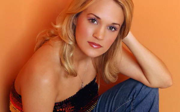 HD desktop wallpaper featuring a close-up of Carrie Underwood with soft lighting and an orange background, highlighting her music career.