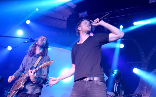 HD desktop wallpaper of American alternative band Imagine Dragons performing live under blue stage lights.