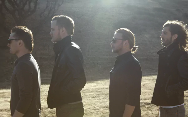 A 4K Ultra HD background featuring the American alternative band Imagine Dragons, showcasing the members standing in a line against a sunlit landscape.