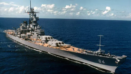 HD desktop wallpaper showing the USS Wisconsin (BB-64), a powerful military battleship warship sailing on a clear ocean under a partly cloudy sky.