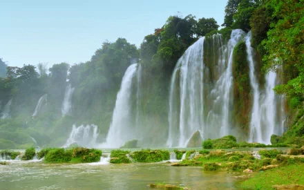 HD wallpaper of Ban Gioc-Detian Falls in Vietnam, showcasing cascading waterfalls surrounded by lush vegetation and clear water, epitomizing the serene beauty of nature.