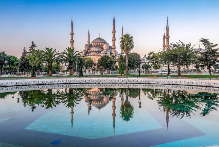 HD desktop wallpaper of the Sultan Ahmed Mosque in Istanbul, Turkey, showcasing its majestic domes and minarets reflected in a tranquil pool.