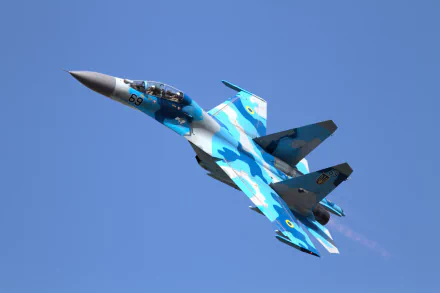A Sukhoi Su-27 jet of the Ukrainian Air Force soars through a clear blue sky, showcasing its striking camouflage pattern in this high-definition wallpaper.