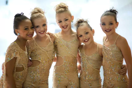 HD desktop wallpaper featuring young dancers from Dance Moms in sparkling costumes, smiling together.