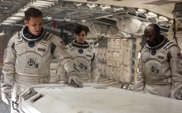 Interstellar movie scene: three astronauts in white suits examine a table inside a spacecraft—cinematic 5K Ultra HD PC desktop wallpaper and background.