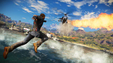 Rico Rodriguez from Just Cause leaps through the air as a helicopter fires in an action-packed scene from Just Cause 3. This HD wallpaper captures the game's thrilling atmosphere.