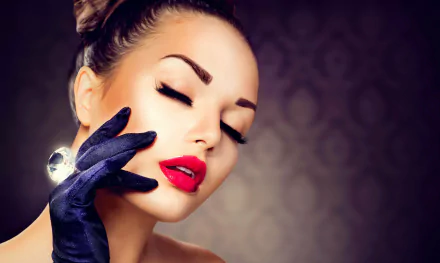 Close-up 8K Ultra HD desktop wallpaper: glamorous woman's face with red lips and long lashes, eyes closed, gloved hand touching her cheek against a subtle patterned backdrop.