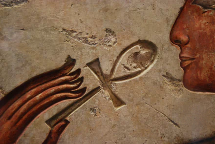 Artistic Egyptian relief showing an ankh between a stylized hand and a profile face on weathered stone, 2K Quad HD PC desktop wallpaper/background.