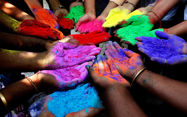 A vibrant display of hands adorned with colorful powders for the Holi festival, creating a festive atmosphere in this HD desktop wallpaper.