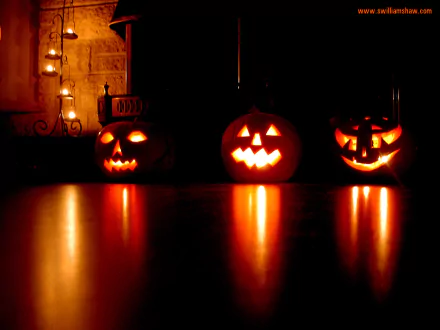 HD desktop wallpaper featuring three glowing jack-o’-lanterns on a reflective surface, set against a dark, festive Halloween background.