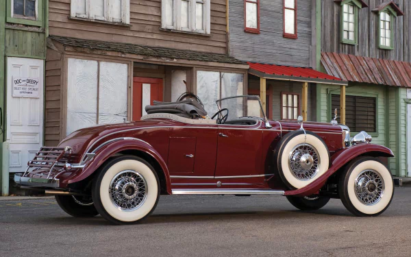 HD desktop wallpaper featuring a maroon 1931 Cadillac convertible parked in front of vintage wooden buildings.