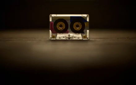 HD PC desktop wallpaper of a vintage audio cassette centered on a dark background with warm spotlight, music-themed.