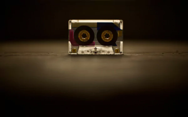 HD PC desktop wallpaper of a vintage audio cassette centered on a dark background with warm spotlight, music-themed.