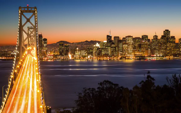 4K Ultra HD PC desktop wallpaper: San Francisco city skyline at dusk with the illuminated Bay Bridge and man-made lights reflecting across the bay.