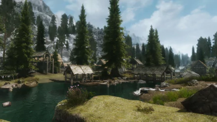 HD desktop wallpaper featuring a serene village scene from The Elder Scrolls V: Skyrim, with wooden houses, tall pine trees, a river, and distant mountains under a partly cloudy sky.