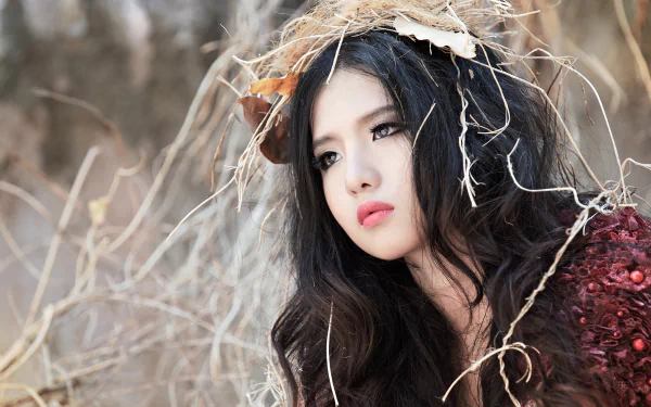 HD wallpaper of a Vietnamese model named Mitu Kat, featuring an Asian woman with long dark hair adorned with natural elements, set against a serene, earthy background.