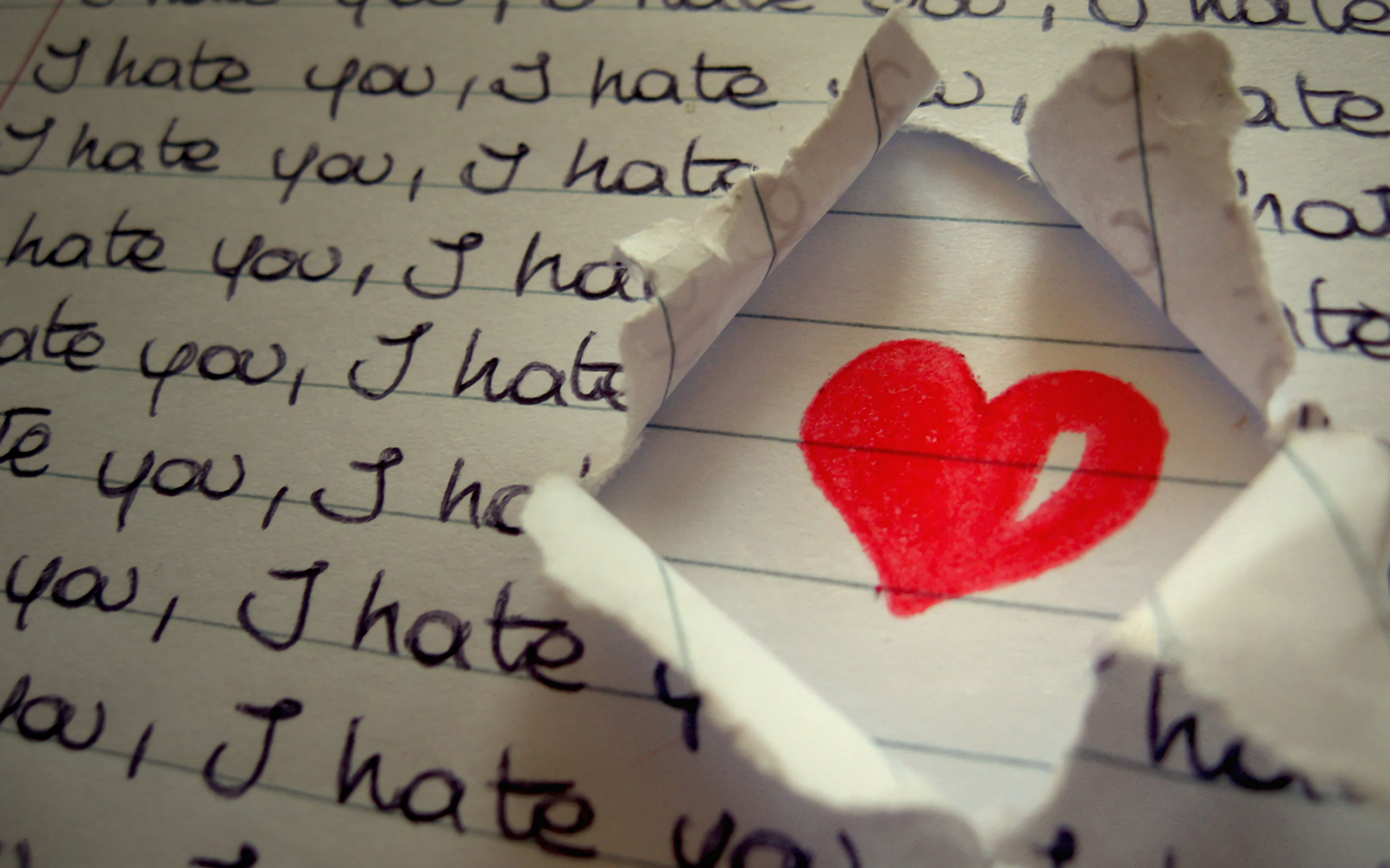 Red heart pierced by a nail on a crumpled paper background, symbolizing The heart under hate message.