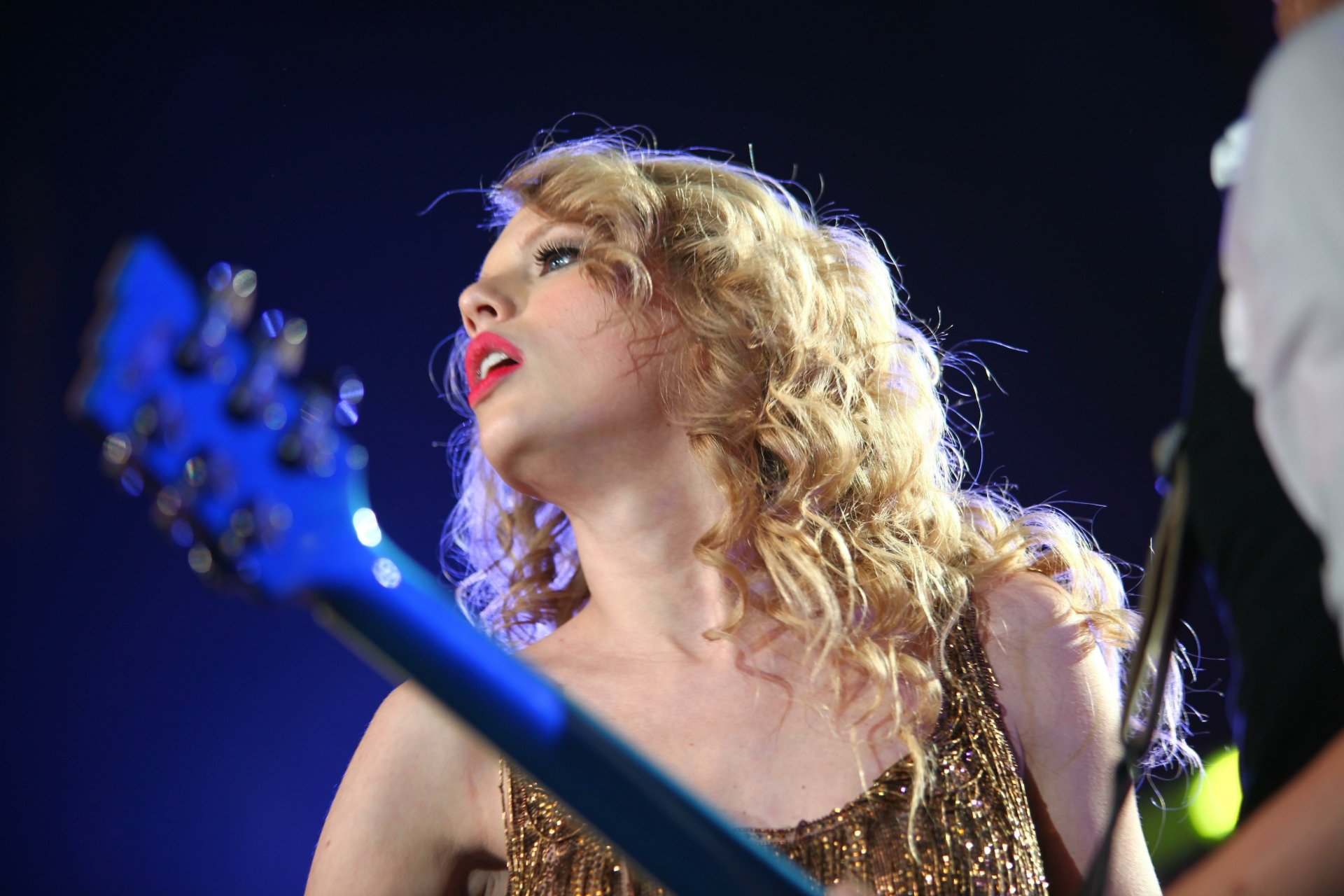 Blonde female singer with guitar onstage under blue lights, shown as a 5K Ultra HD PC desktop wallpaper and background.