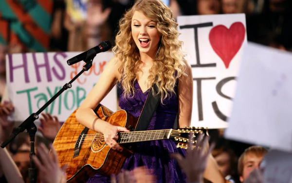 4K Ultra HD PC wallpaper: female pop singer with curly hair playing an acoustic guitar onstage, cheering crowd and fan signs (image tagged Taylor Swift).