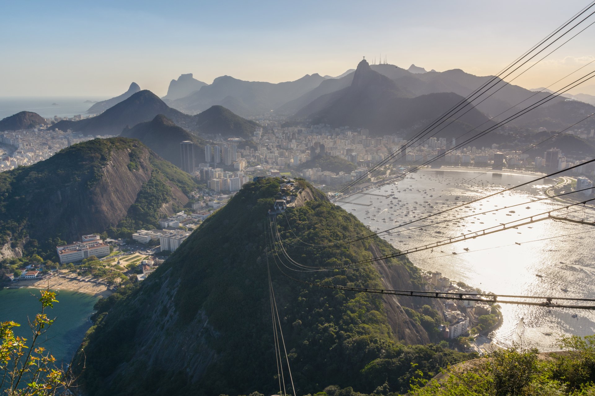 5K Ultra HD desktop wallpaper of Sugarloaf Mountain in Rio de Janeiro, Brazil, showing the bay, urban skyline and cable car lines over a man-made cityscape at sunrise.