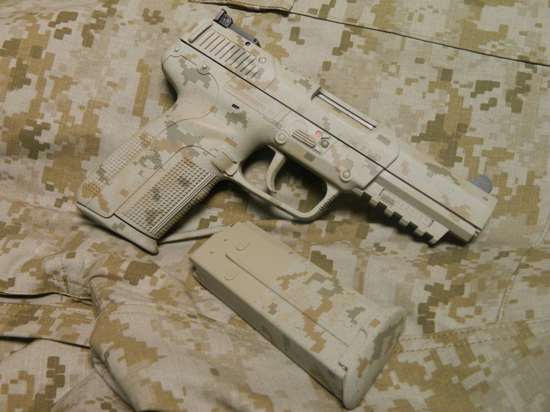 HD desktop wallpaper featuring a man-made pistol with a desert camouflage pattern resting on matching camouflage fabric.