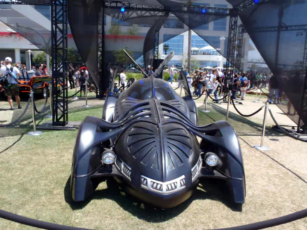 A detailed view of the Batmobile on display, showcasing its sleek design amidst a lively crowd, perfect for a 4K Ultra HD PC desktop wallpaper and background.