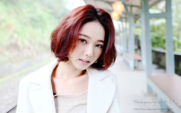 A Taiwanese woman with stylish short hair poses elegantly in a serene setting, featuring bokeh effects that enhance this HD wallpaper background.