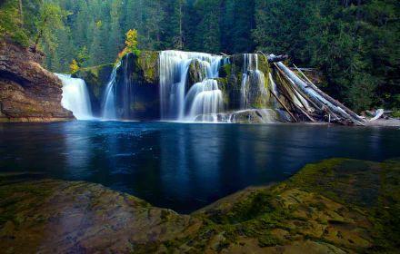 HD desktop wallpaper of a majestic waterfall cascading into a serene lake surrounded by lush forest.
