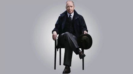 HD desktop wallpaper featuring James Spader from The Blacklist, seated on a chair, dressed in a coat and holding a hat.