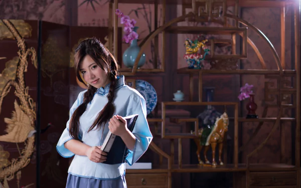 A Taiwanese model, Chén Sīyǐng, poses elegantly in a traditional setting, holding a book, surrounded by decorative elements. This image serves as a striking 4K Ultra HD wallpaper.