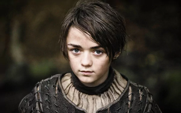 HD desktop wallpaper featuring Maisie Williams as Arya Stark from the TV show Game of Thrones, showcasing her in character with a serious expression against a dark, blurred background.