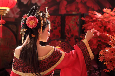 A Taiwanese woman in a traditional costume adorned with flowers and intricate hair accessories stands against a backdrop of vibrant red foliage, showcasing elegance and cultural heritage.