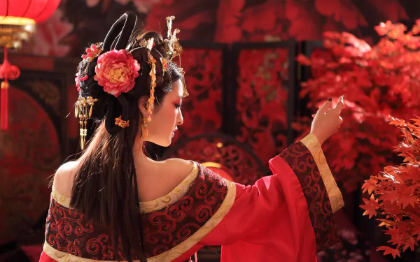 A Taiwanese woman in a traditional costume adorned with flowers and intricate hair accessories stands against a backdrop of vibrant red foliage, showcasing elegance and cultural heritage.