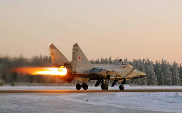 HD desktop wallpaper showing a Mikoyan MiG-31 military jet with afterburners engaged on a snowy runway at sunrise.