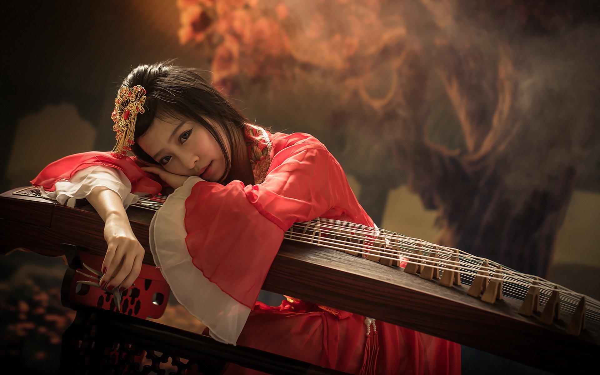 HD wallpaper featuring an Asian woman in traditional attire, resting on a string instrument against a springtime backdrop.