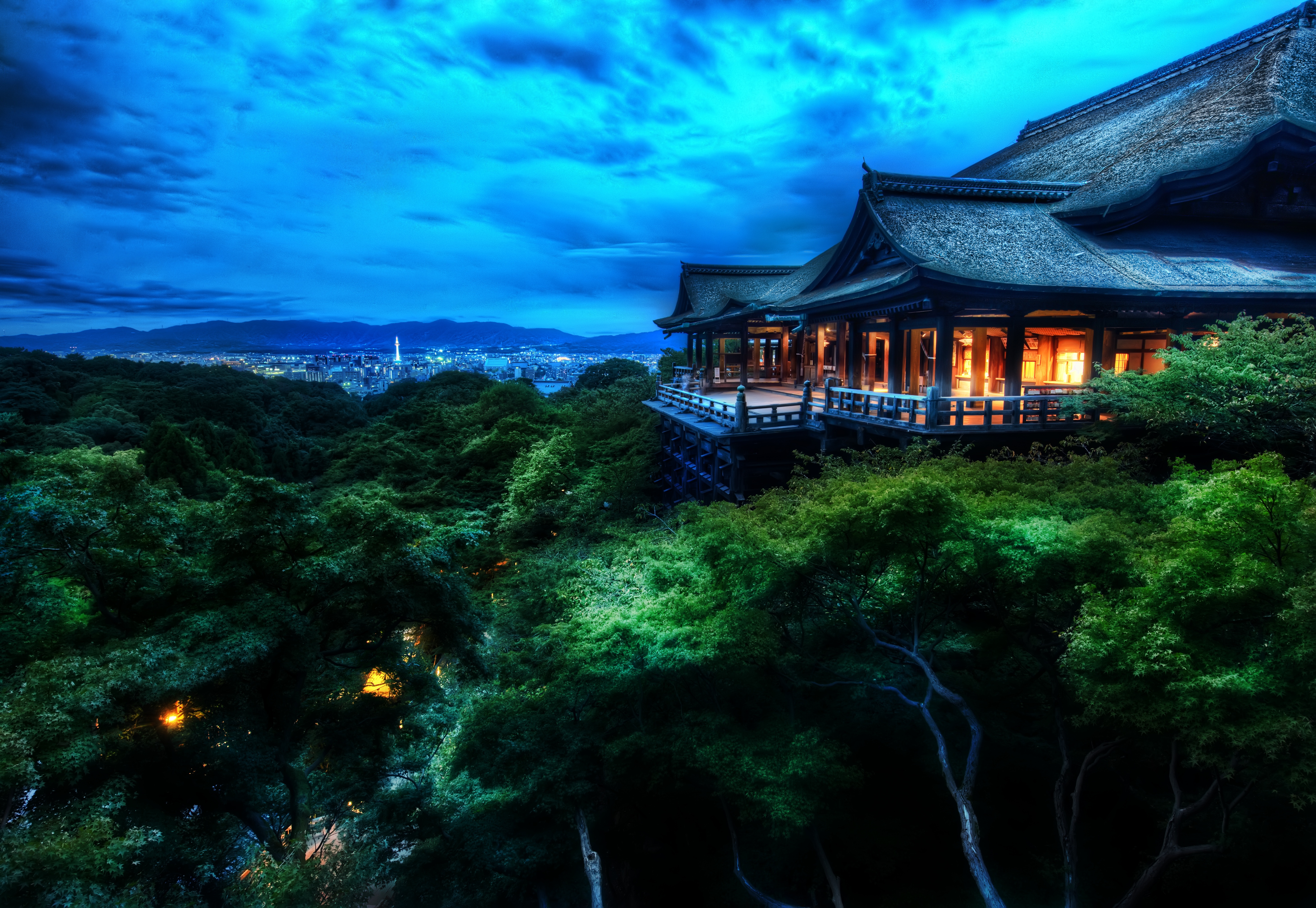 HD wallpaper of Kiyomizu-dera Temple in Kyoto, Japan, illuminated at night, showcasing its stunning architecture amidst lush greenery.