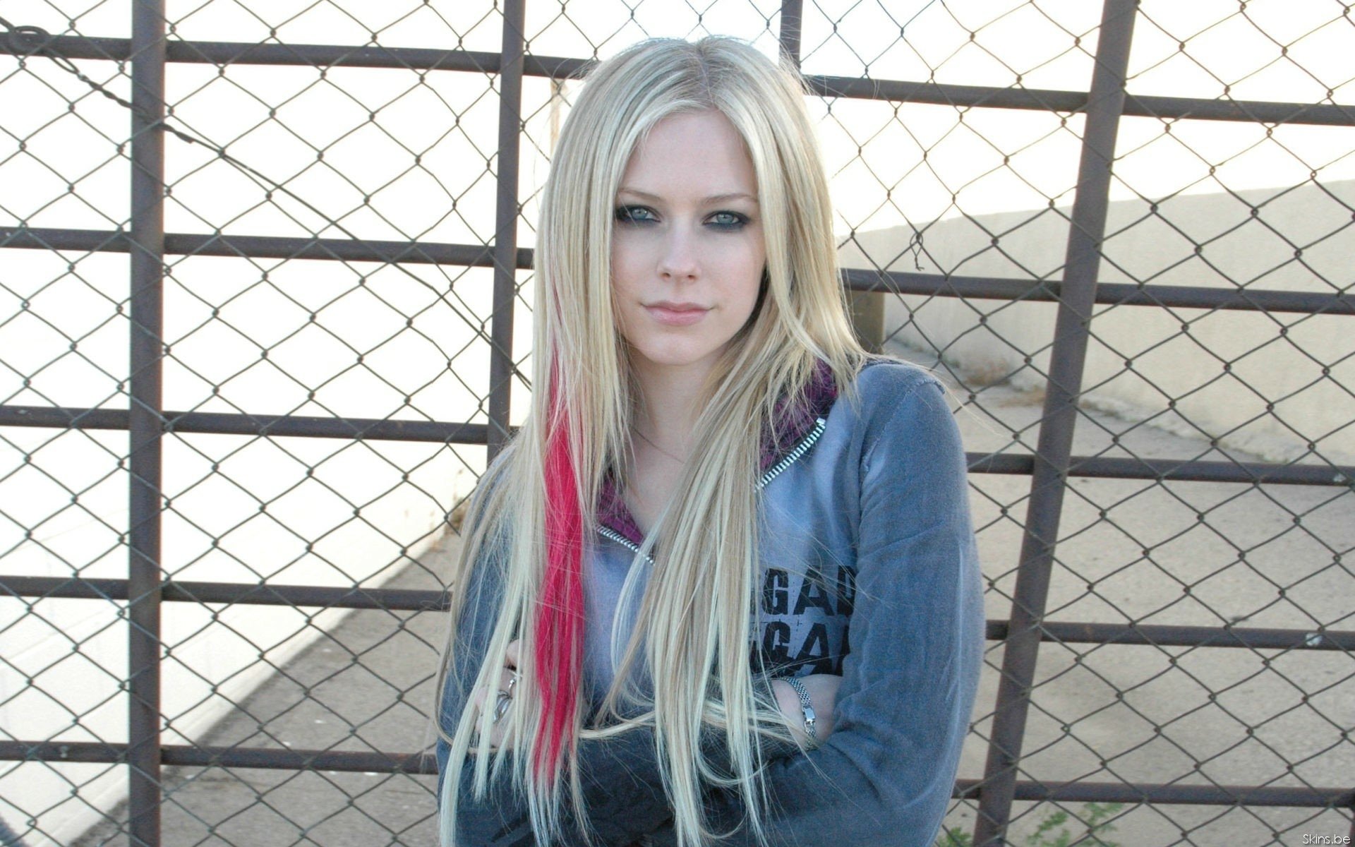 Avril Lavigne poses against a fence, showcasing her signature style. This vibrant HD PC desktop wallpaper captures the essence of her music and personality.