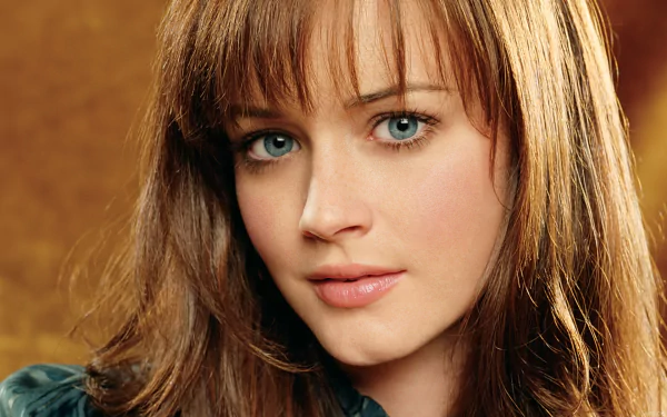 HD desktop wallpaper featuring a close-up portrait of celebrity Alexis Bledel with blue eyes and brown hair against a warm, blurred background.