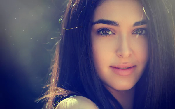 A close-up portrait of a smiling woman with long dark hair, set against a softly blurred background, creating a serene and inviting atmosphere. 4K Ultra HD quality enhances the detail.